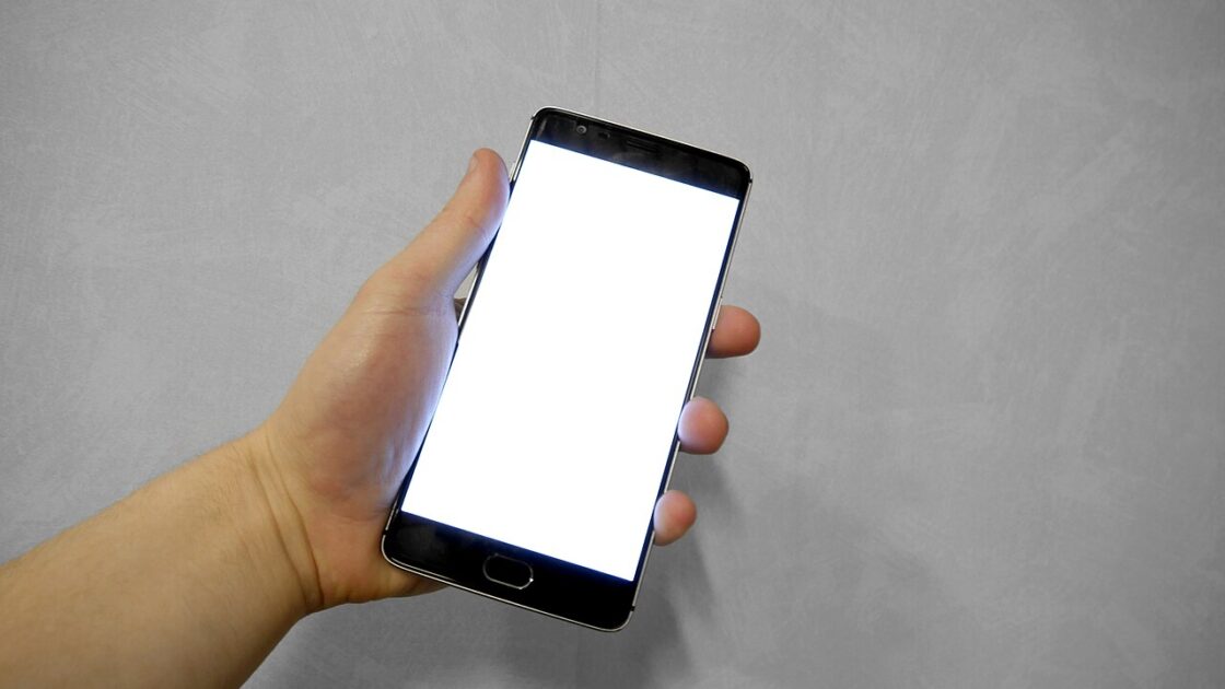 Tangan memegang ponsel dengan layar putih kosong