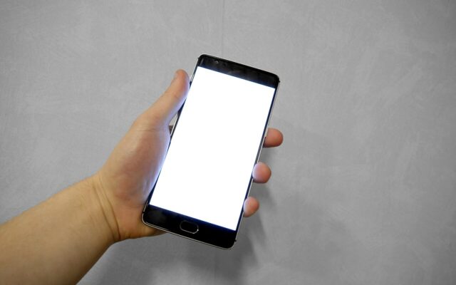 Tangan memegang ponsel dengan layar putih kosong